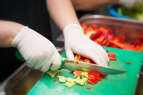 Employee wearing gloves chopping peppers