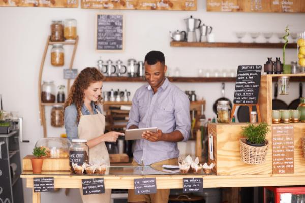 Two employees using a tablet at the front counter of a restaurant