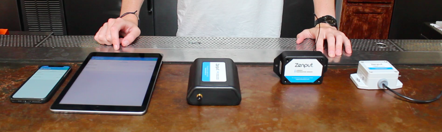 Photo of all devices needed to use Zenput Temp Monitoring, including a gateway, sensor, and smartphone.