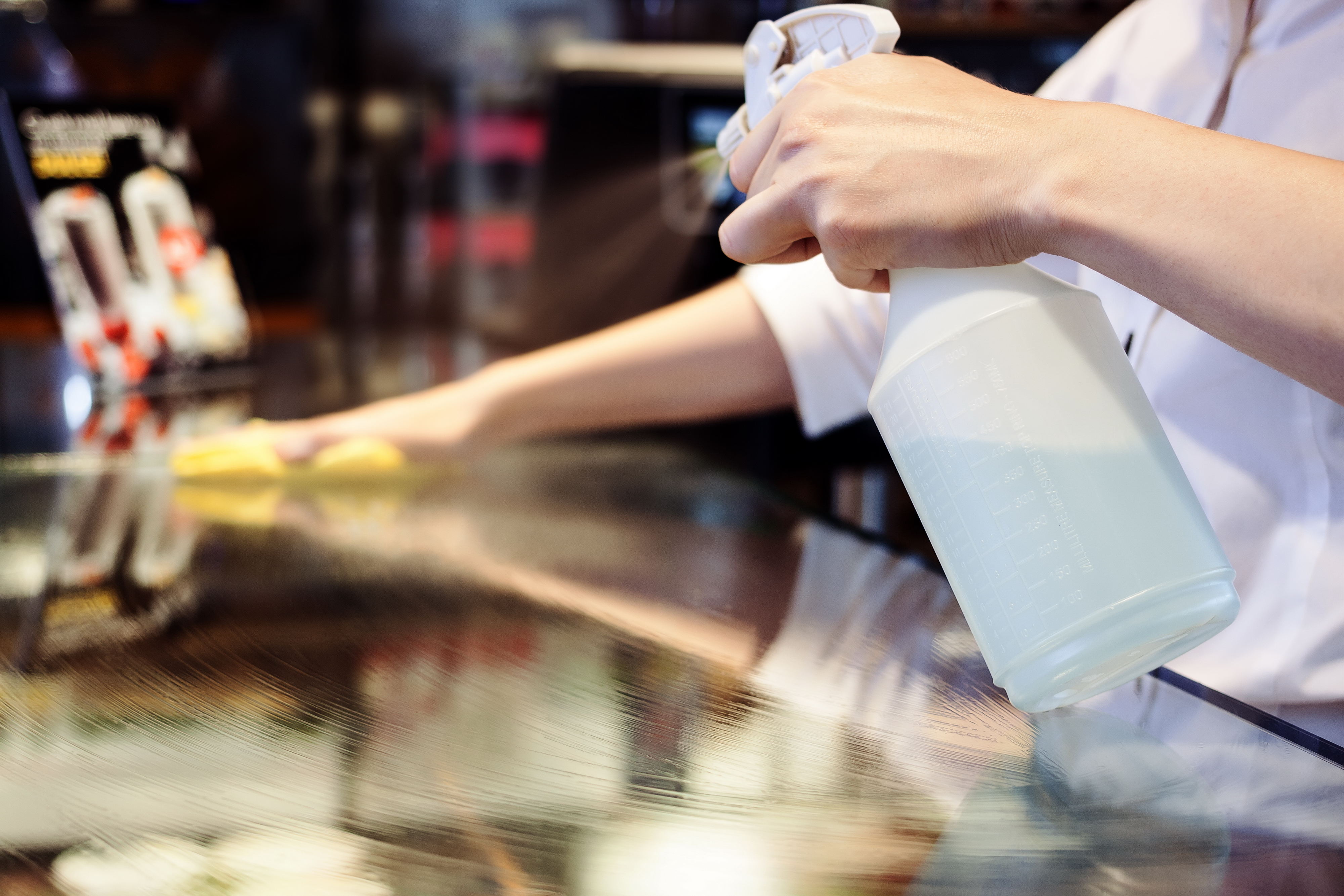 A person with gloves on cleaning the surface of a table.