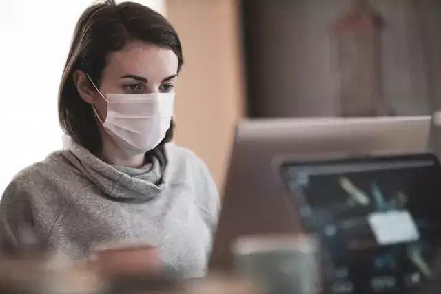 woman wearing mask on computer